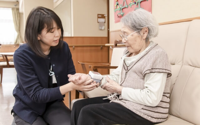 利用者の血圧を測る女性職員